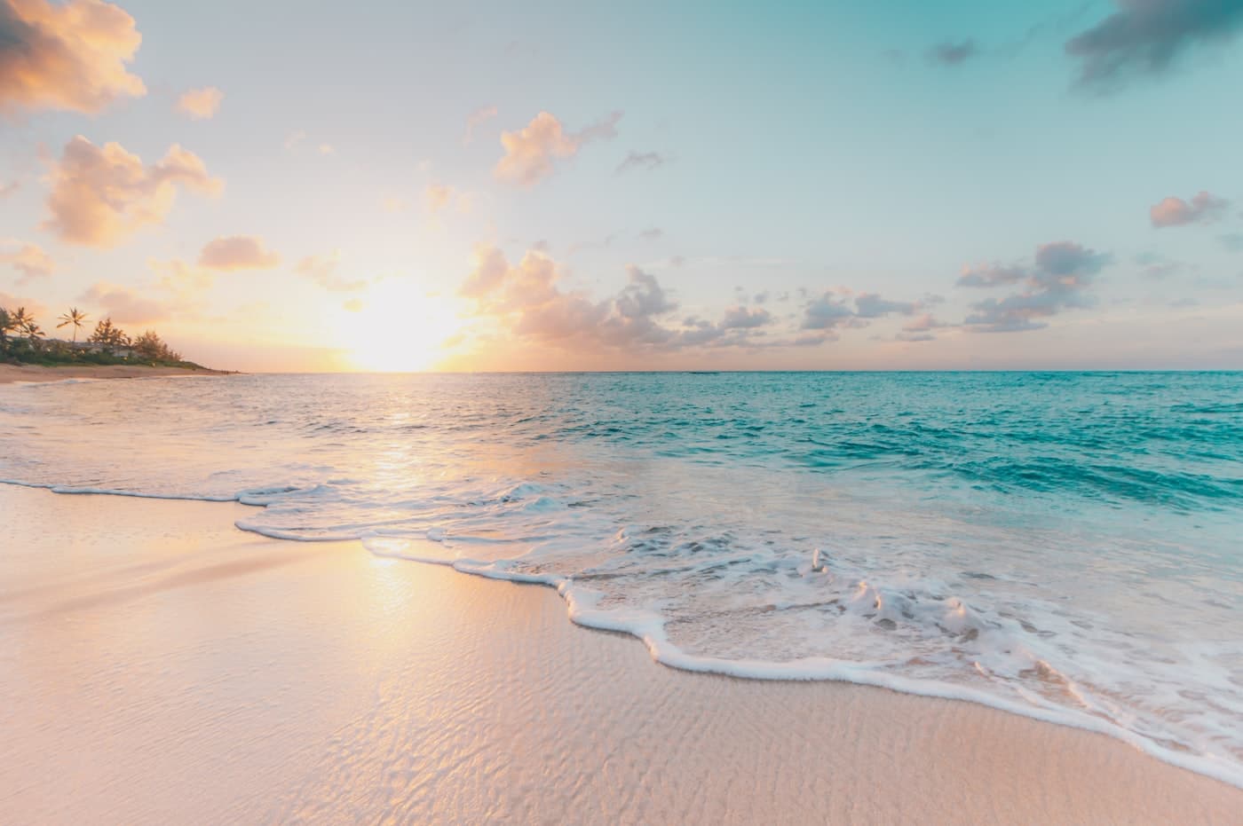 An empty beach at sunrise with clear shallow water
