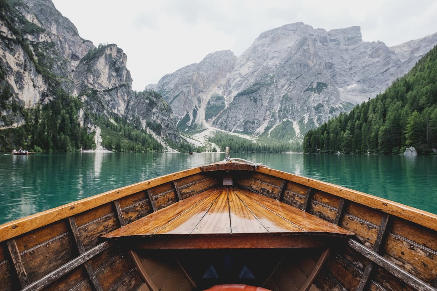 A wooden boat on a still alpine lake below the mountains