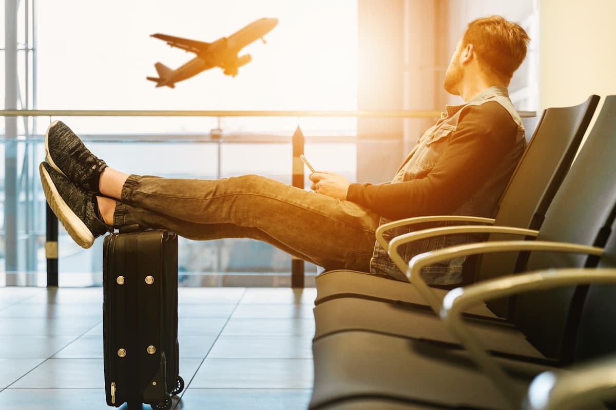 A traveller waiting at the gate as an aircraft climbs away